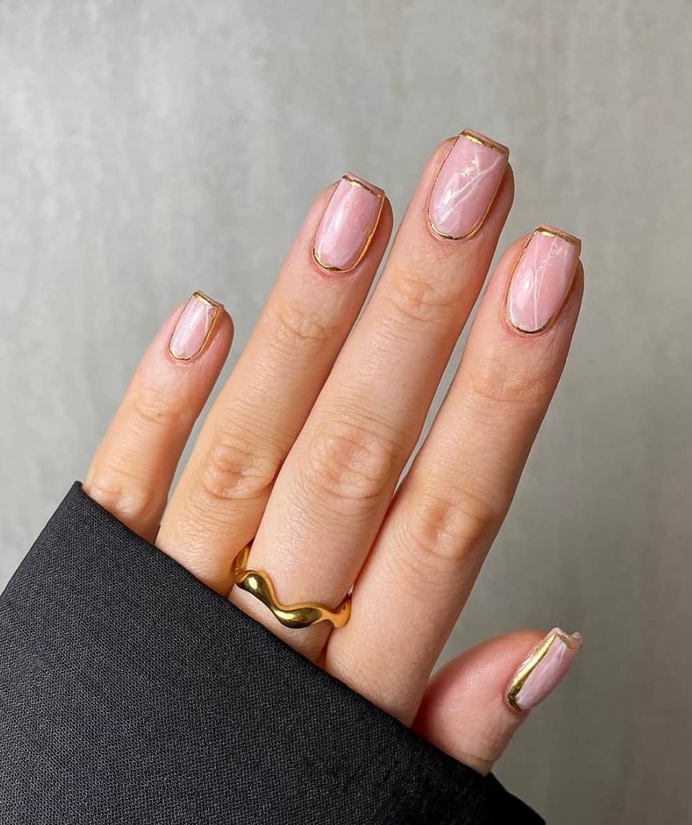 image of a hand with nude marble nails with gold trim