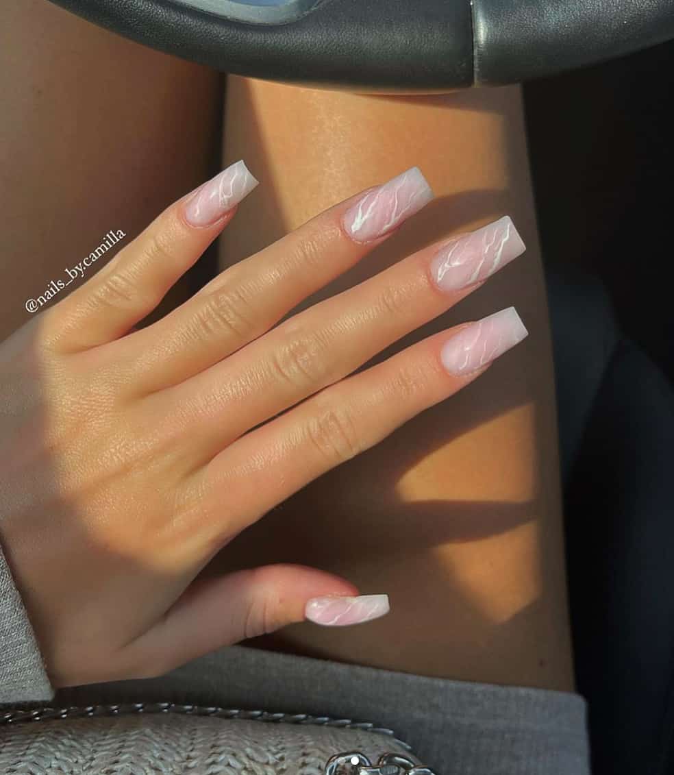 image of a hand with long square acrylic nude marble nails