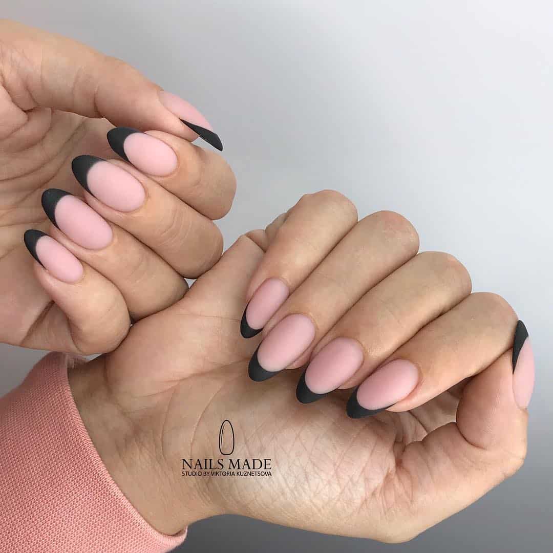 image of two hands with matte nude pink nails with black french tips