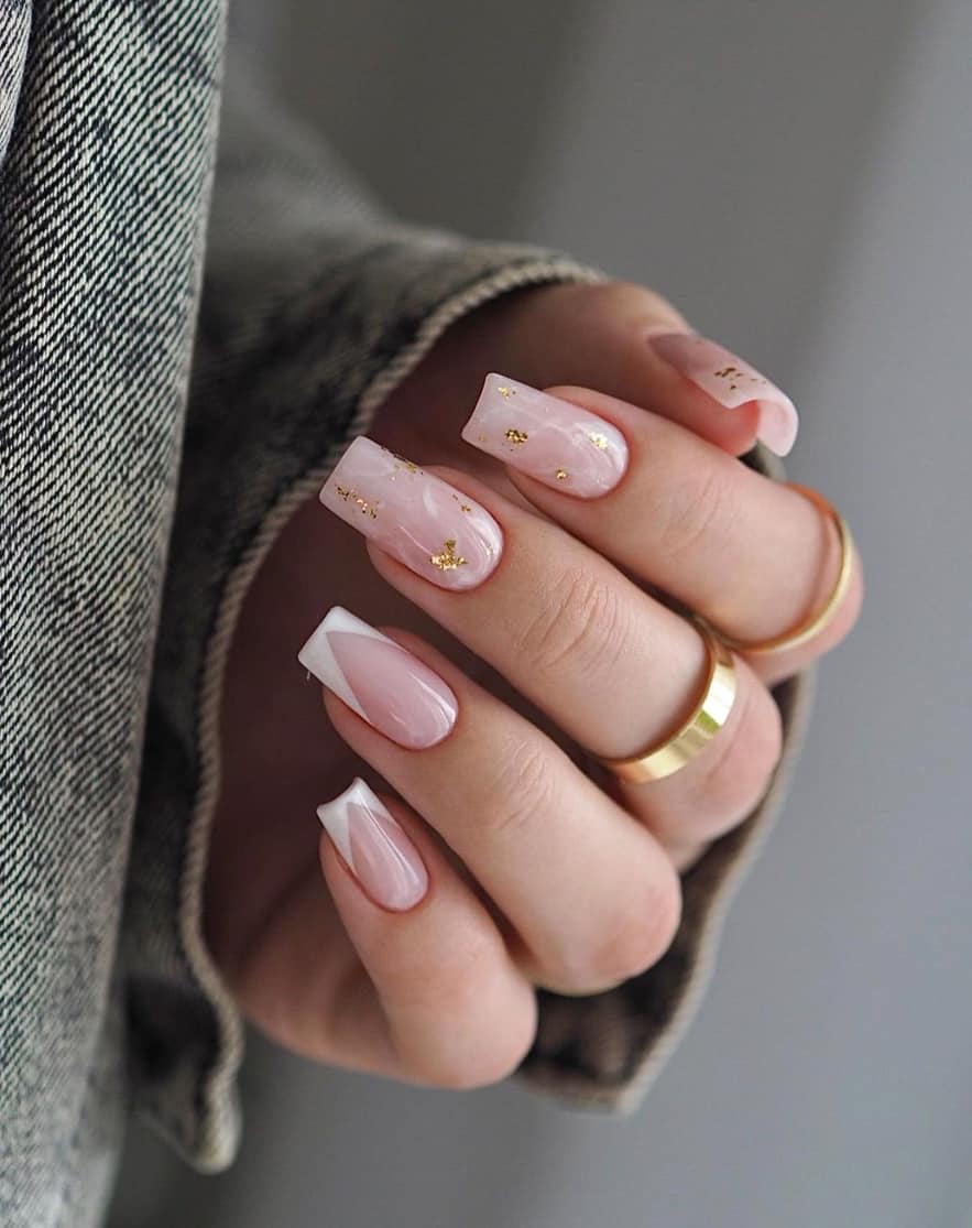 image of a hand with long square nude marble nails with gold accents
