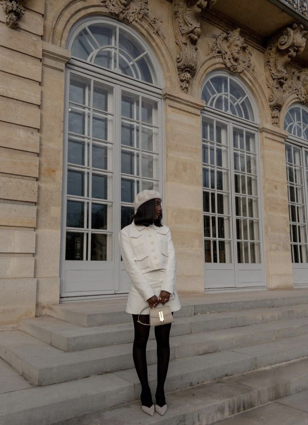 black french woman wearing an ivory beret with an ivory tweed skirt set