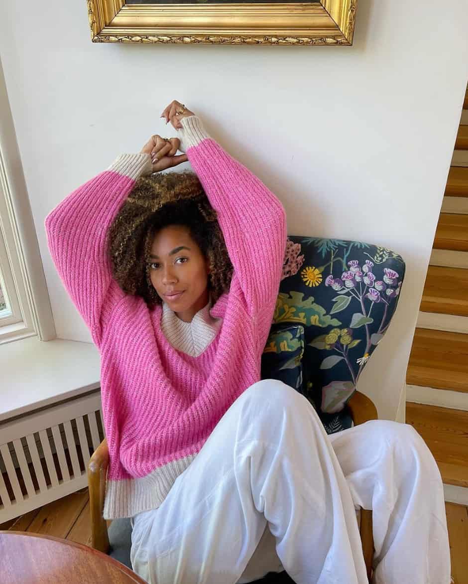 black woman wearing a hot pink oversized sweater with white trousers
