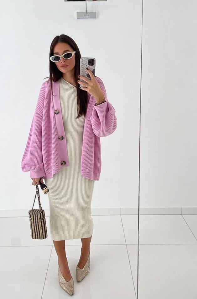 woman wearing an oversized pink cardigan sweater with a knit ribbed cream dress and glittery pumps