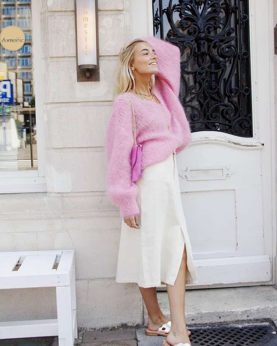 woman wearing a bubblegum pink mohair sweater with a white denim midi skirt and sandals