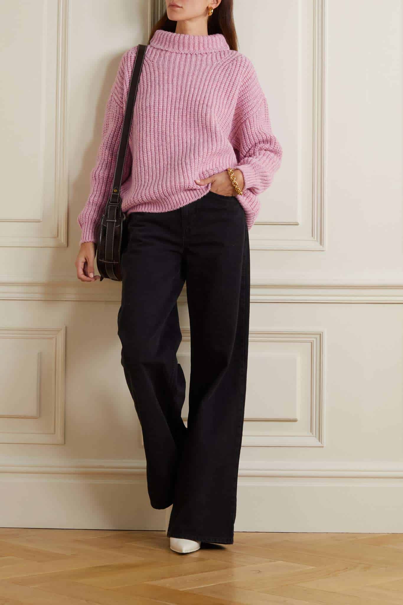 woman wearing a chunky pink mock neck sweater with wide leg black trousers and white heels