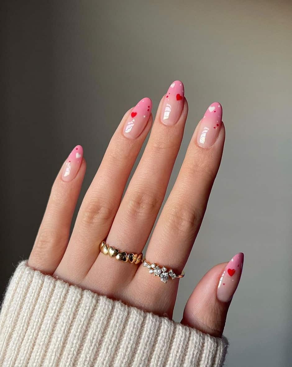 hand with almond nails with light pink and red heart designs
