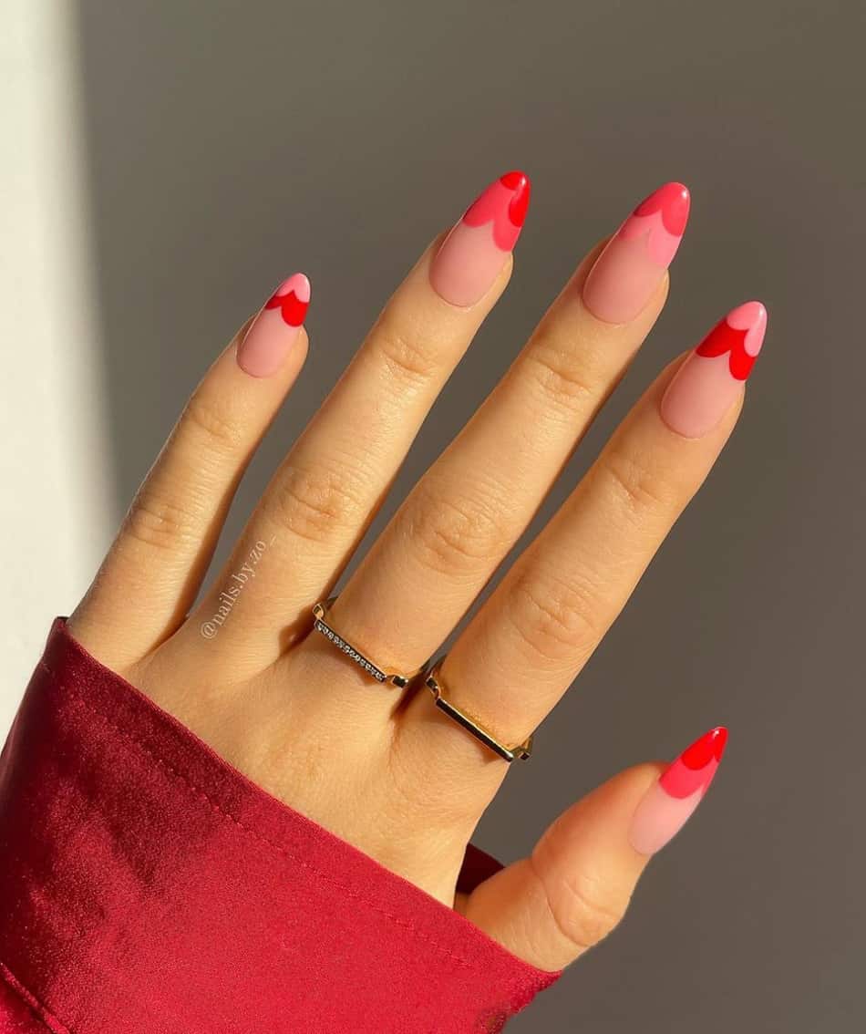 hand with long almond acrylic nails with pink and red wavy french tips