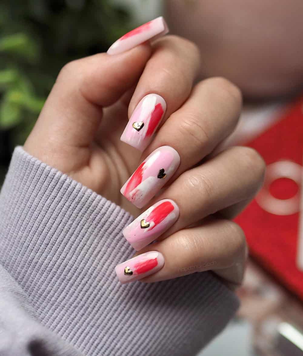 hand with long square acrylic nails with pink, red, and white designs