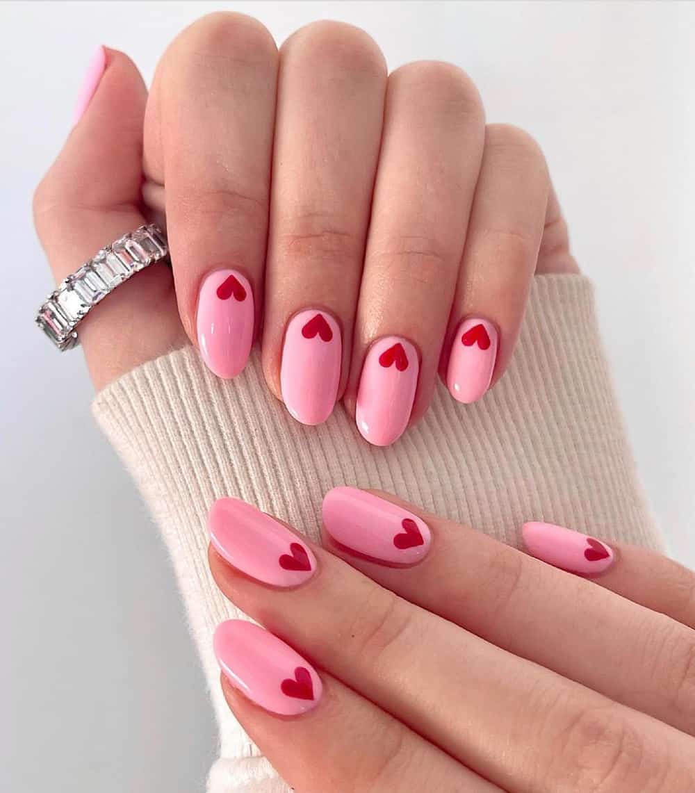 hand with bubblegum pink polished nails with little red hearts