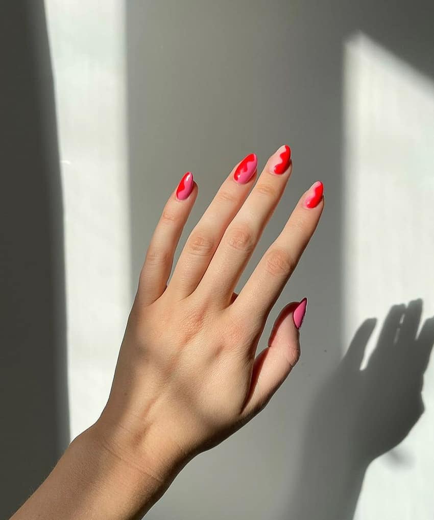 hand with red and pink nails with wavy designs