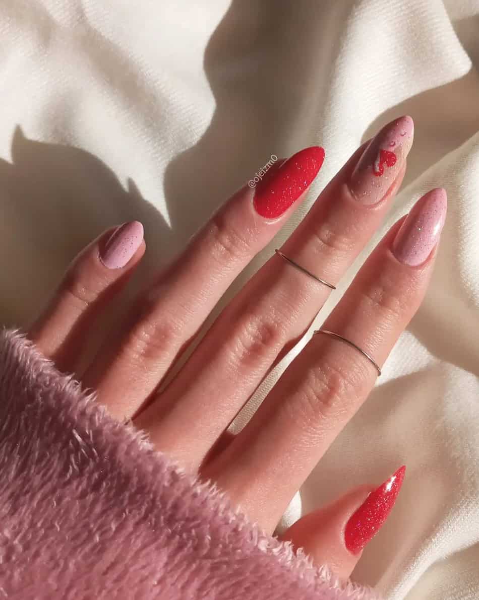 a hand with pink and red glitter nails and heart designs