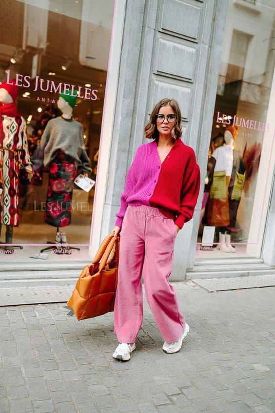 woman wearing a red and pink colorblock cardigan with pink corduroy pants and white sneakers