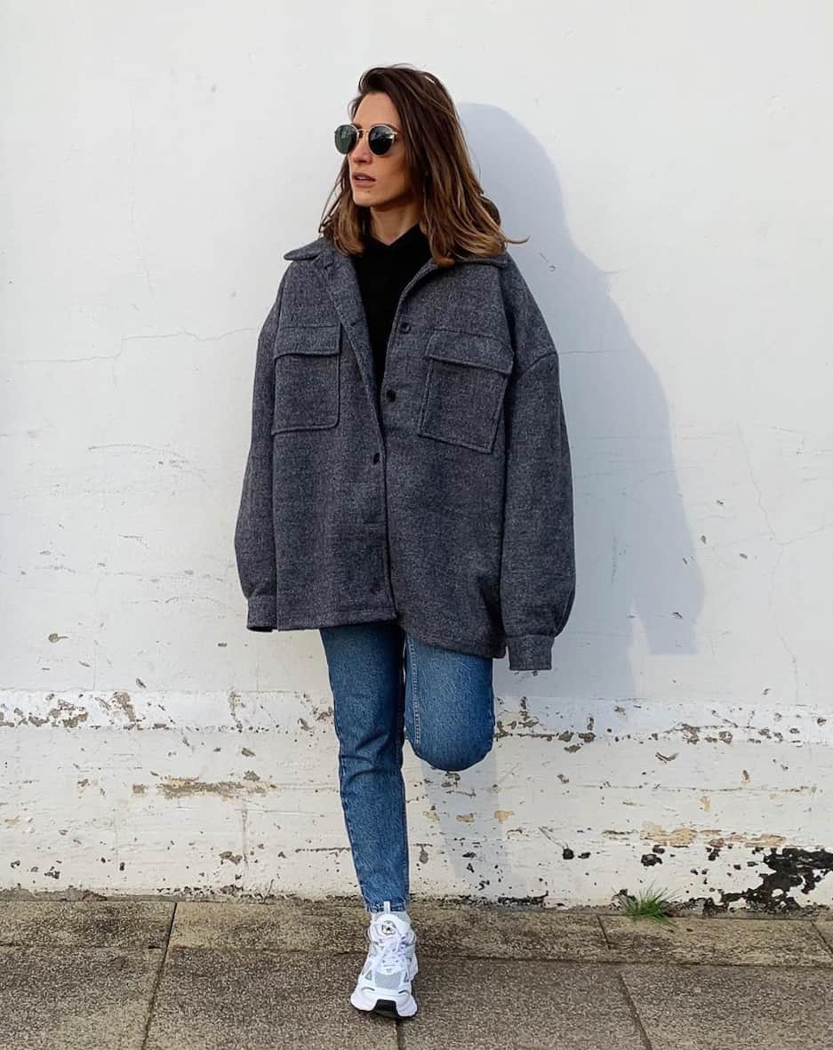 Woman wearing an oversized grey shacket with straight leg denim pants and sneakers.