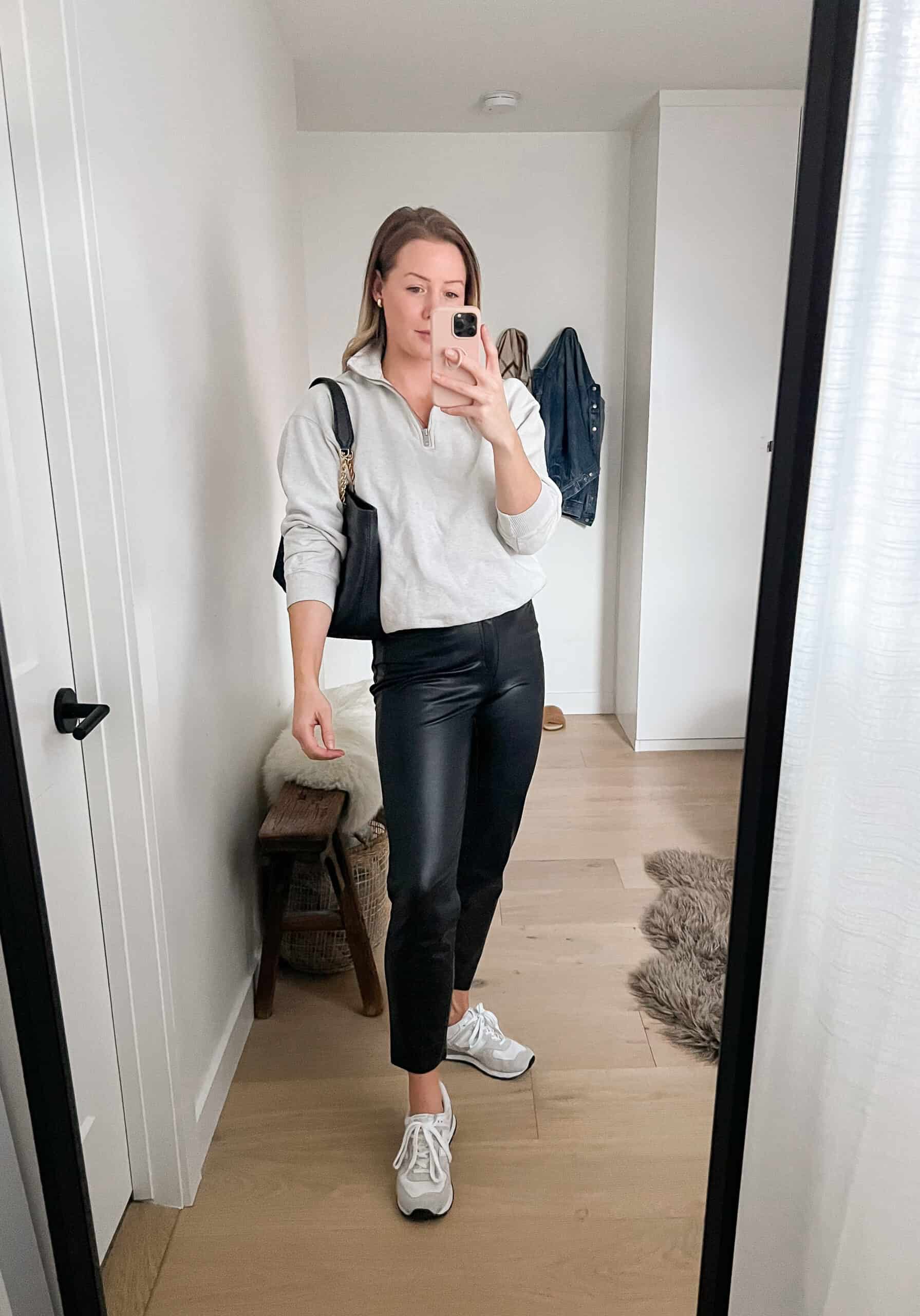 woman wearing a light grey half zip sweatshirt with leather pants and white sneakers