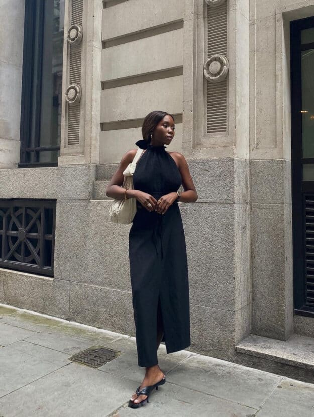 chic black woman wearing a sleeveless black blouse with a long black skirt and pointed heeled mules