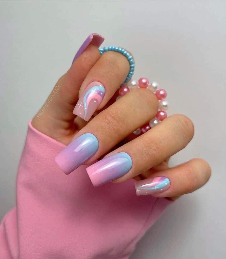An image of a hand with blue, purple, and pink ombre with swirl nail art and sparkles