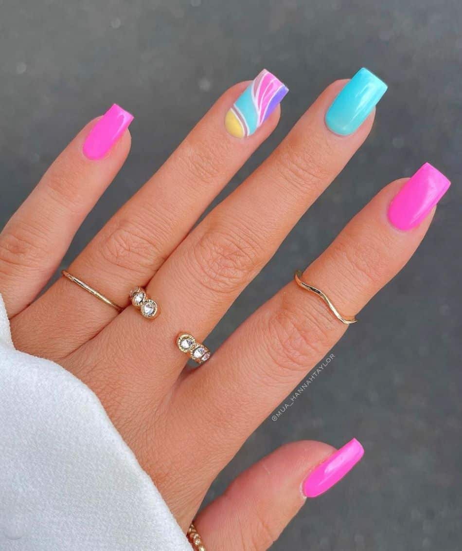An image of a hand with hot pink and light blue nails and a rainbow swirl accent nail 