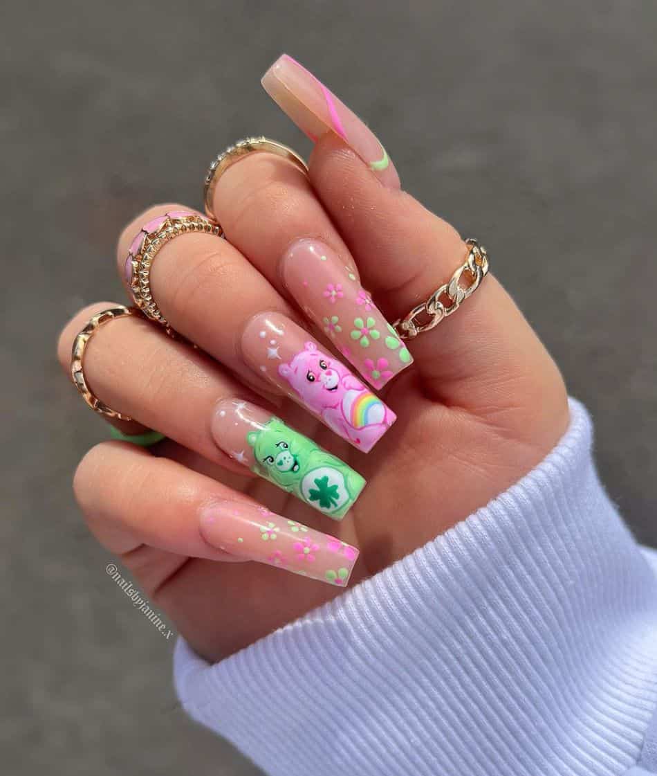An image of a hand with 90s nail design featuring care bear nail art and pink and green flower accents