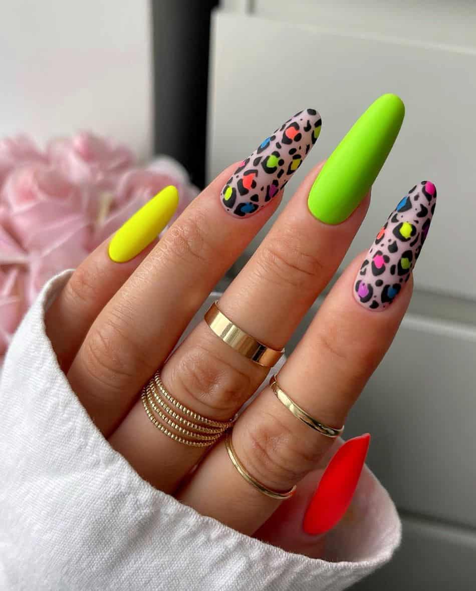 An image of a hand with long neon colored nails and cheetah print accent nails