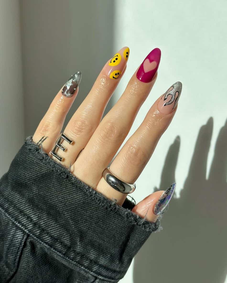 An image of a hand with 90s nail designs such as smiley faces, flame nail art, and silver stars