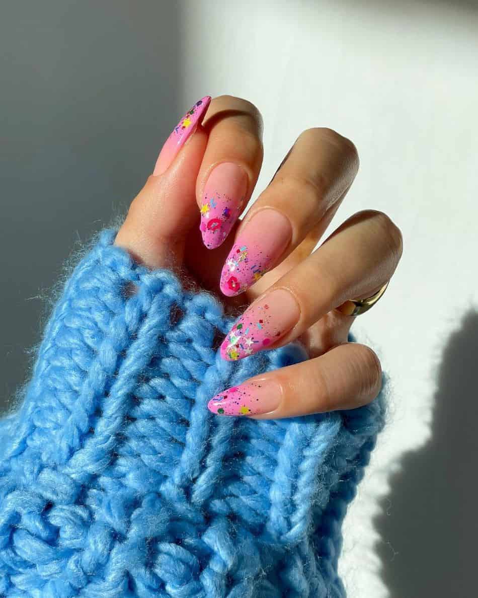 An image of a hand with pink ombre nails and 90s style chunky glitter