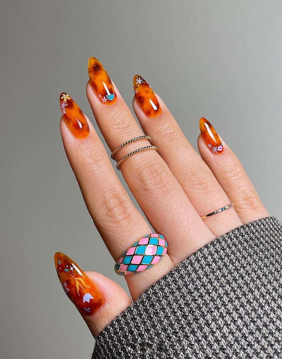 An image of a hand with tortoise shell nail art and flower art accents