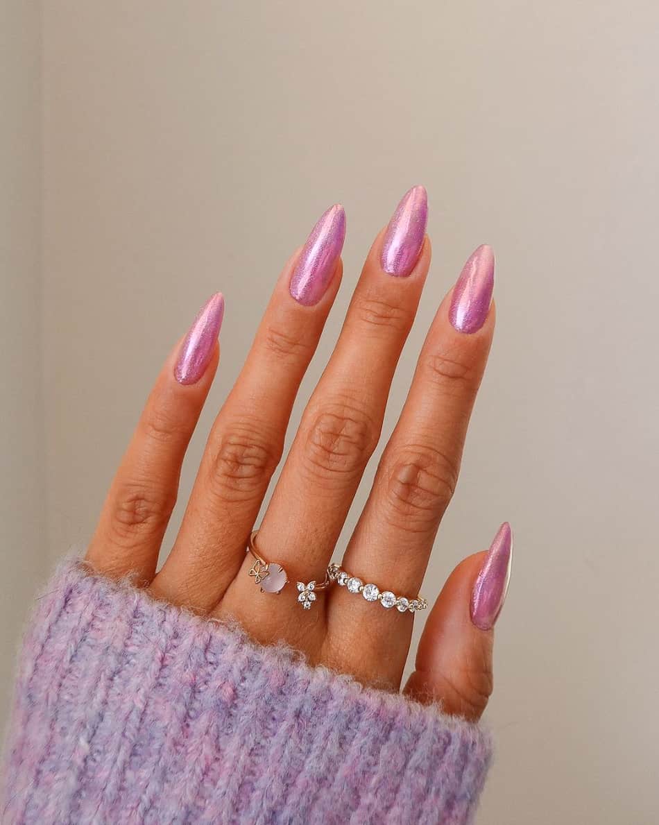 An image of a hand with almond nails and 90s pink chrome polish