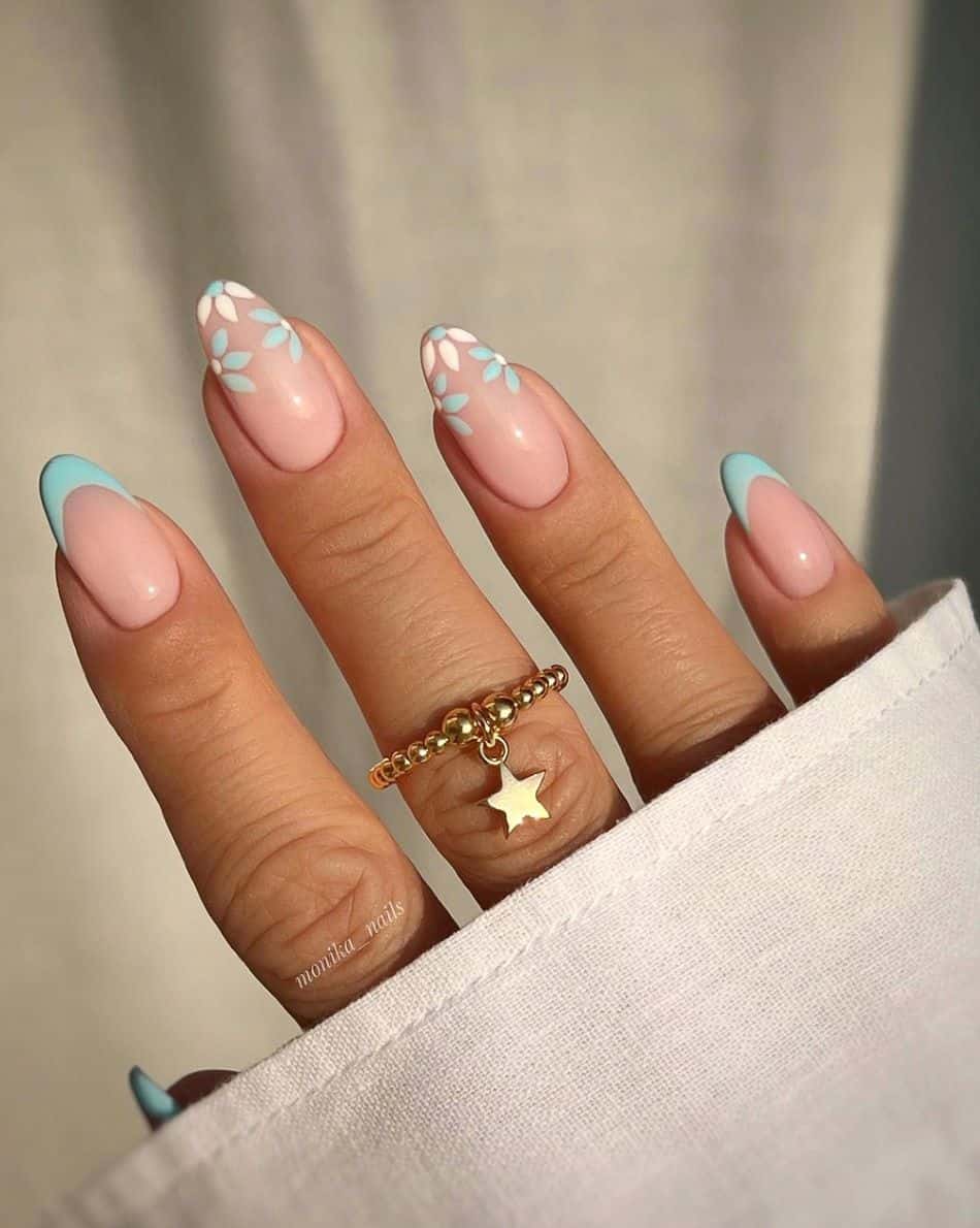 Almond nails with blue French tips and flower accents. 