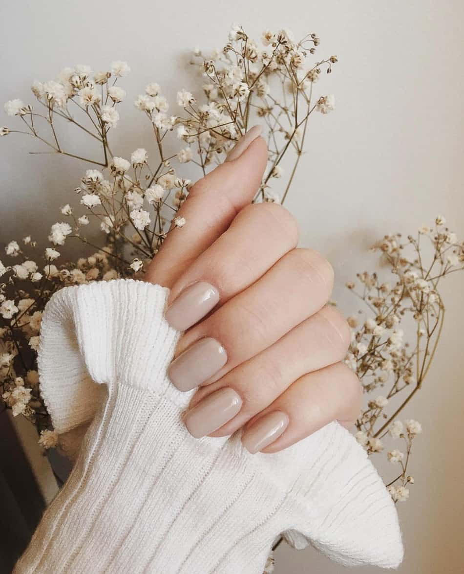 an image of a hand with short square solid-colored beige nails