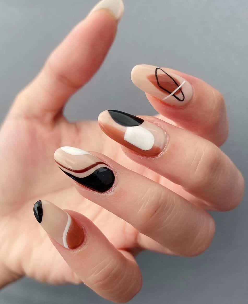 an image of a hand with beige nails with black, brown, and white swirls and abstract patterns