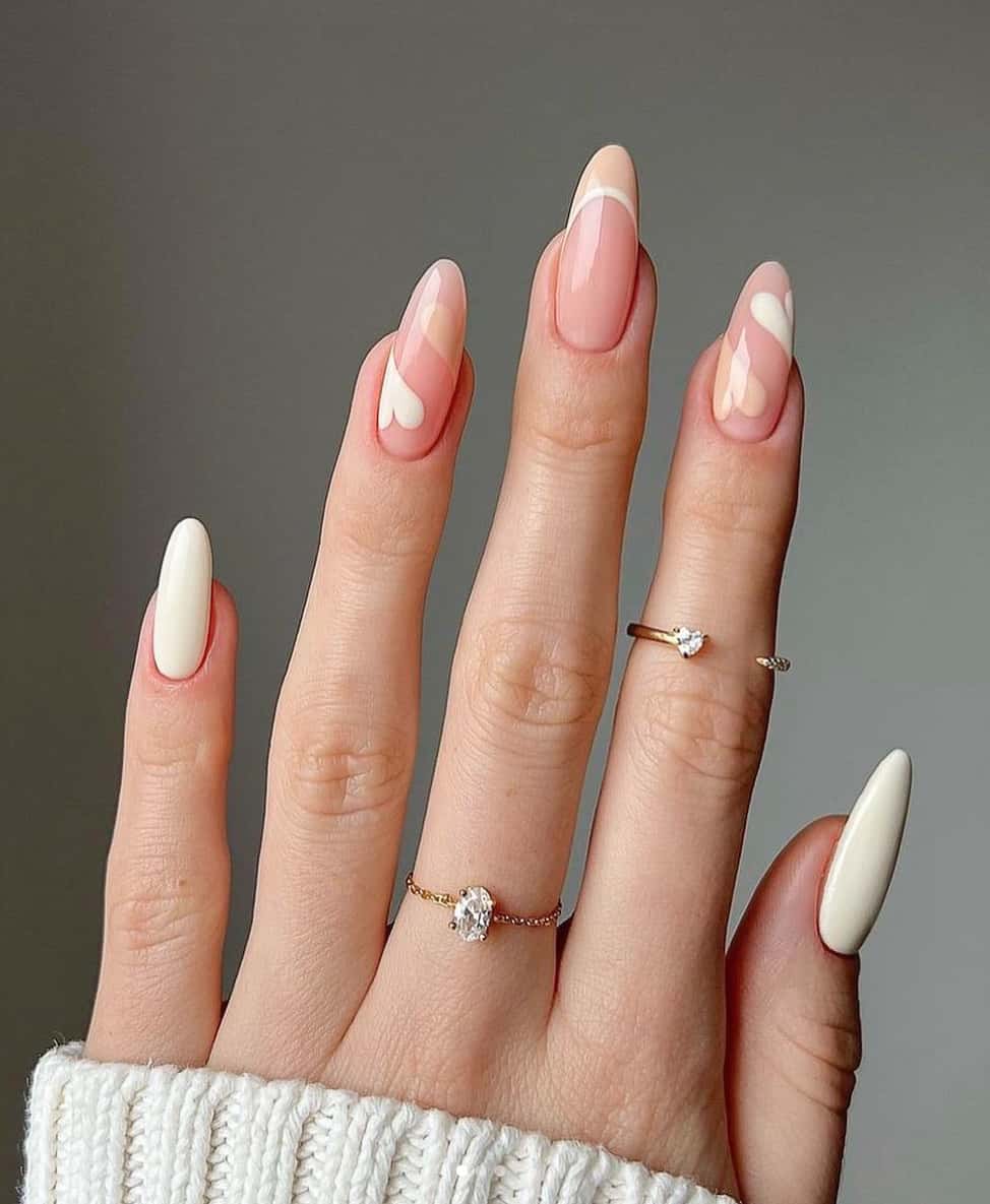 an image of a hand with solid beige nails, beige French tips, and beige heart accents