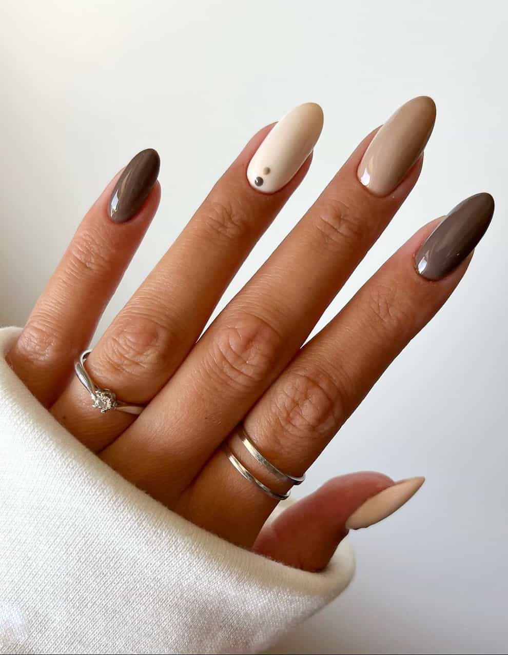 an image of a hand with brown and beige gradient nails and dot accents