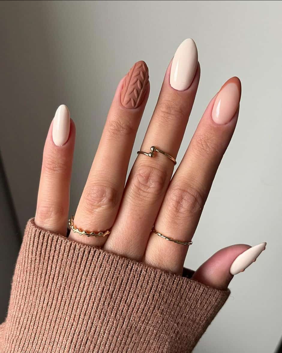 an image of a hand with solid beige nails and terra cotta-colored sweater accent nail