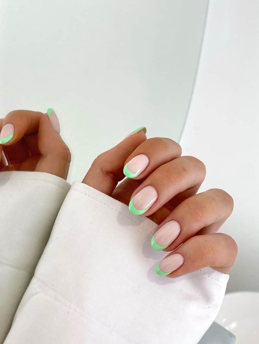 A hand with spring green French tips on round nails