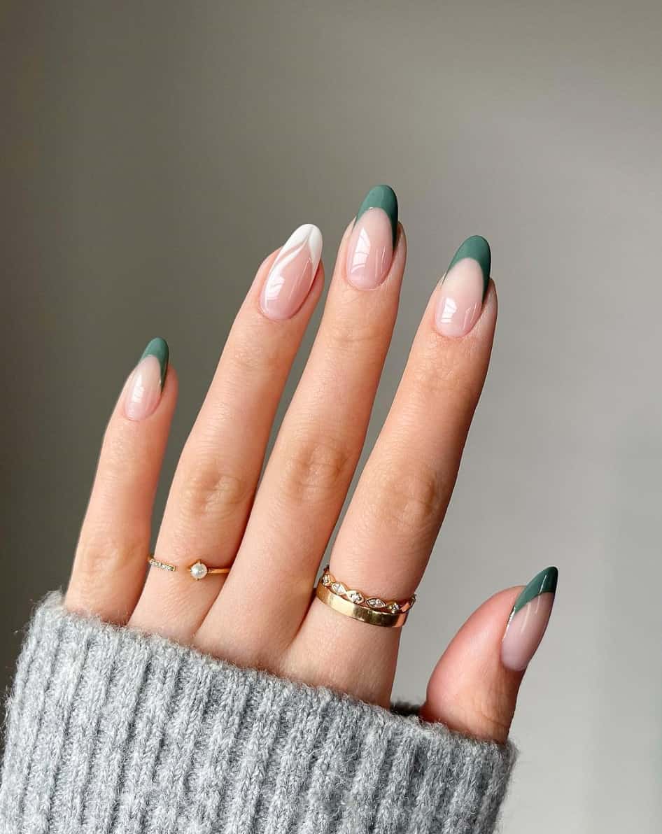 A hand with dark green French tips on almond nails and a white French tipped accent nail