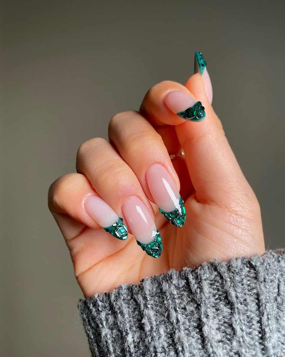 A hand with emerald green French tips and gem accents