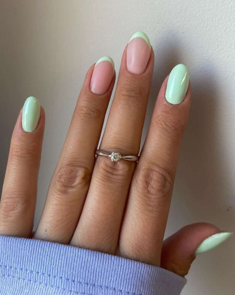 A hand with pastel green nail polish and green French tip accent nails
