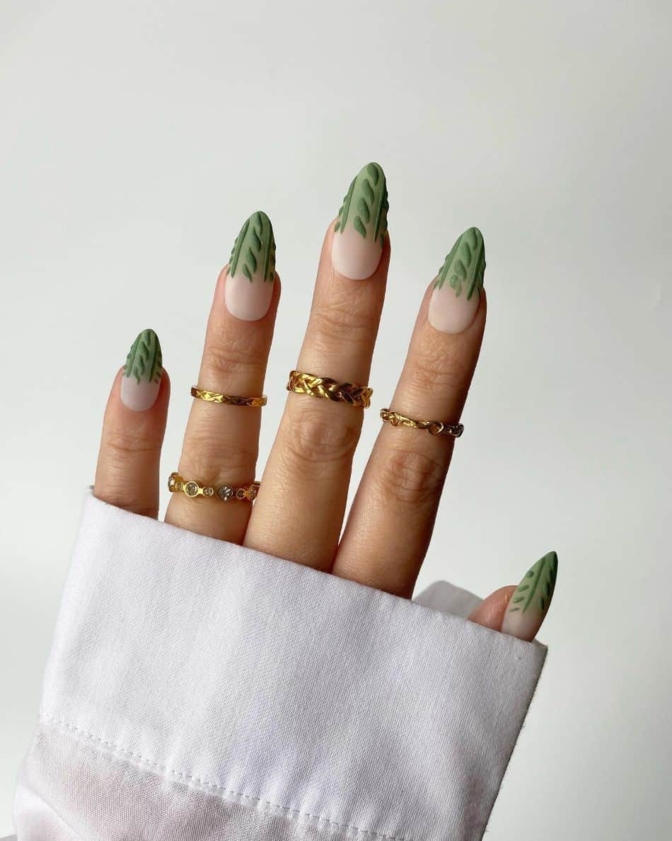 A hand with textured sweater patterned French tips in a dark green