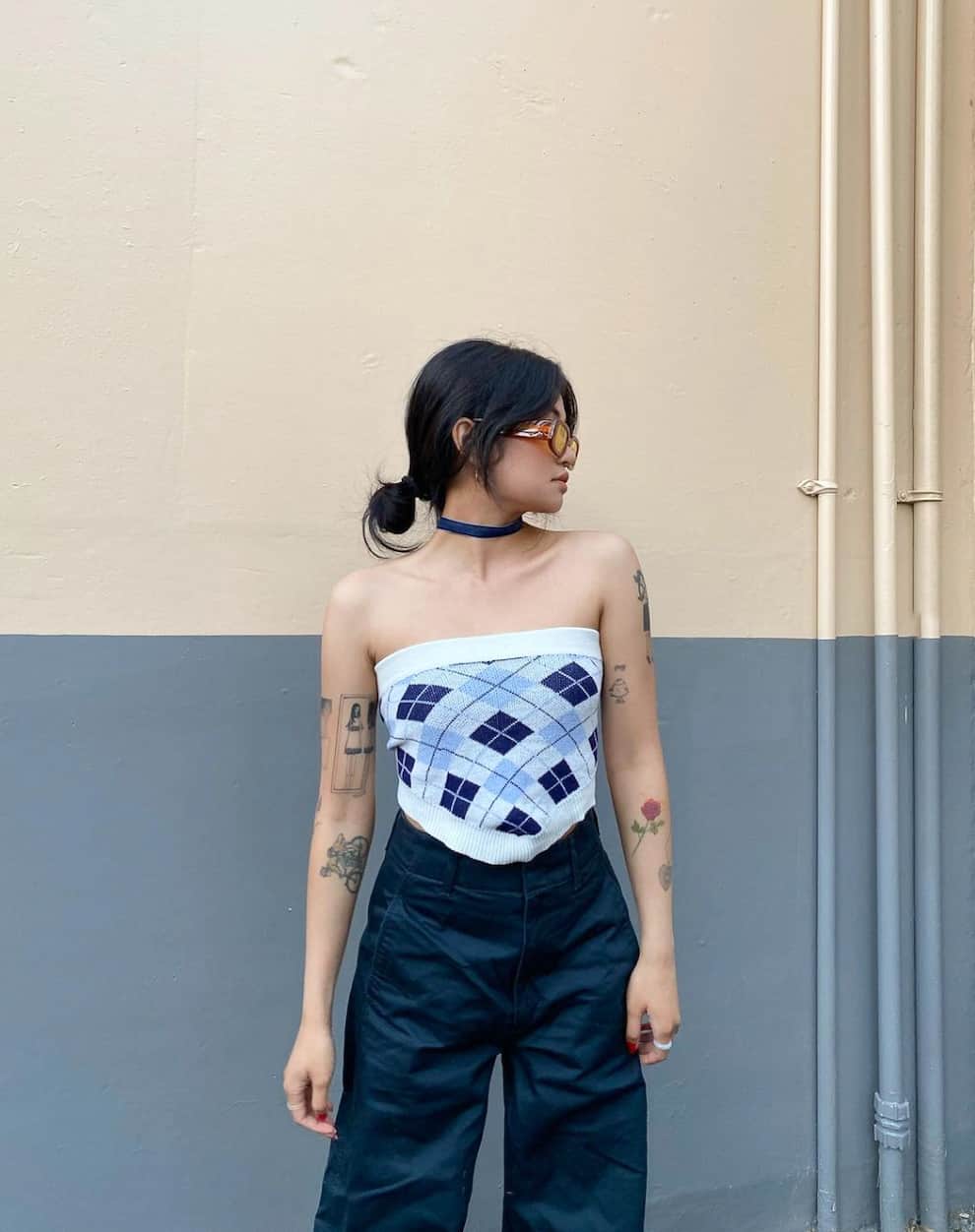 a woman wearing wide leg black pants with an argyle print cropped tube top and sunglasses