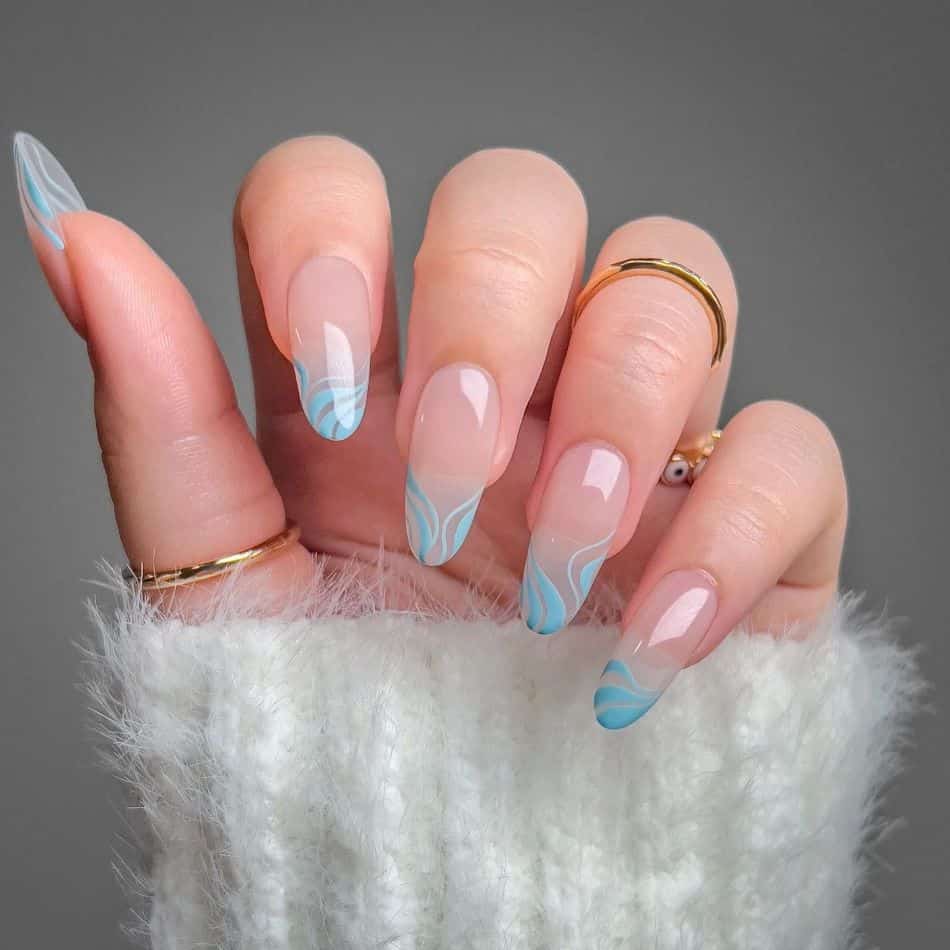 Nude almond nails with pastel blue waves along tips. 