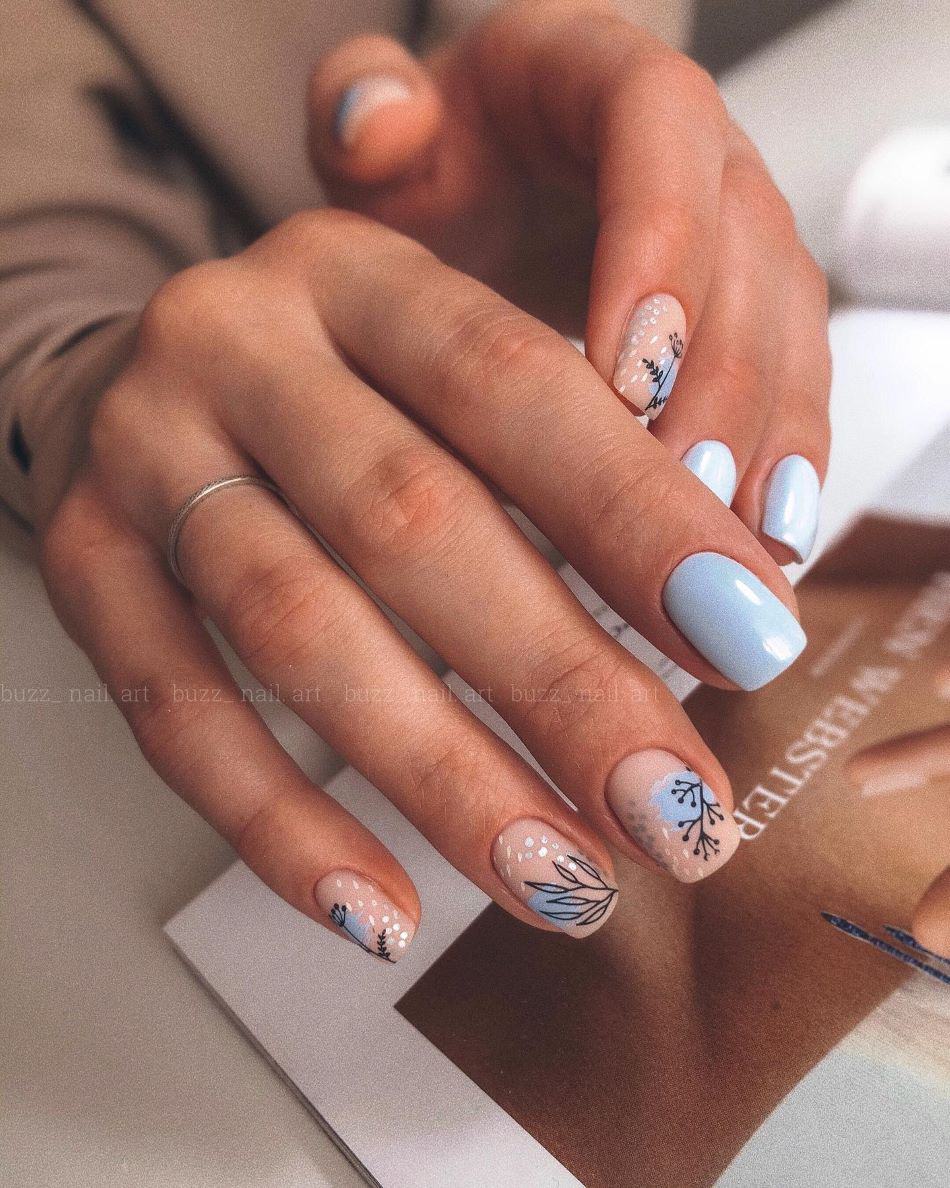 Soft blue and nude nails with silver speckles and black botanical nail art. 