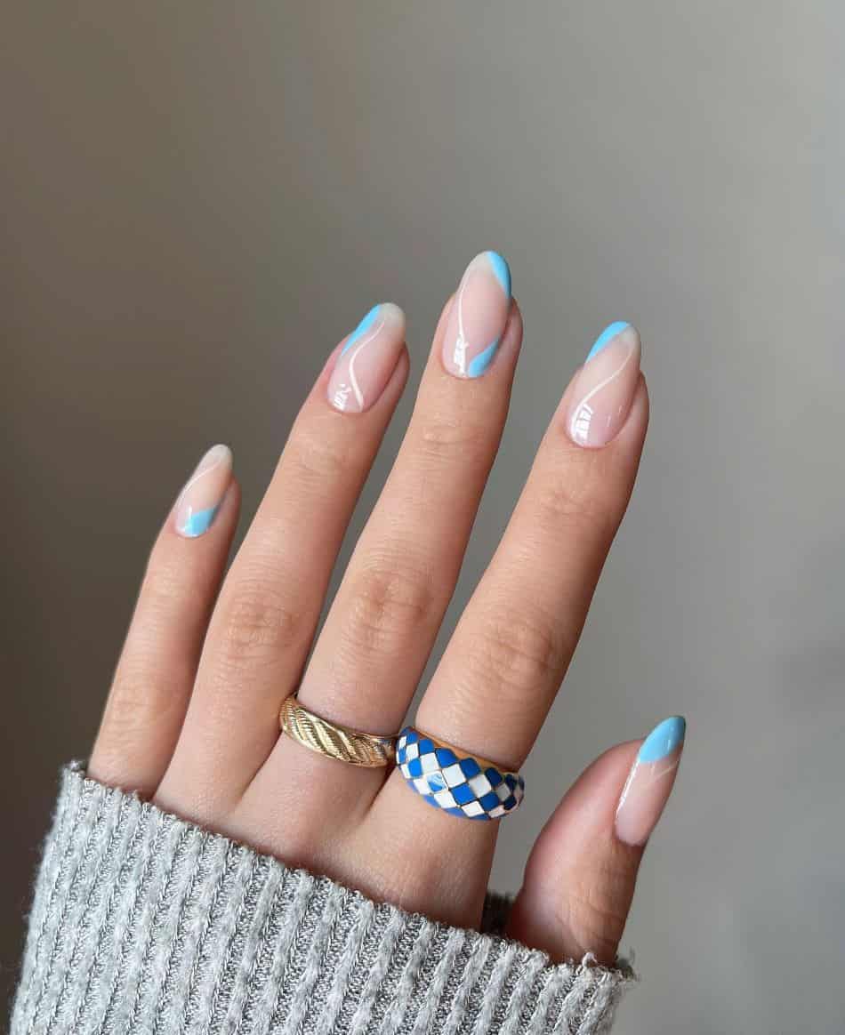 Nude almond nails with blue accents and wavy white lines. 