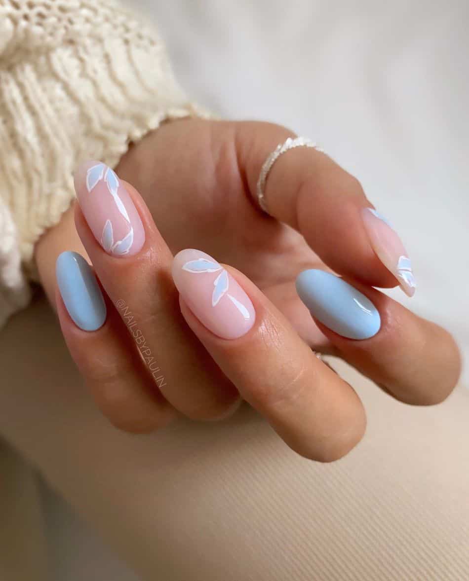 Soft blue and nude almond nails with floral accents. 