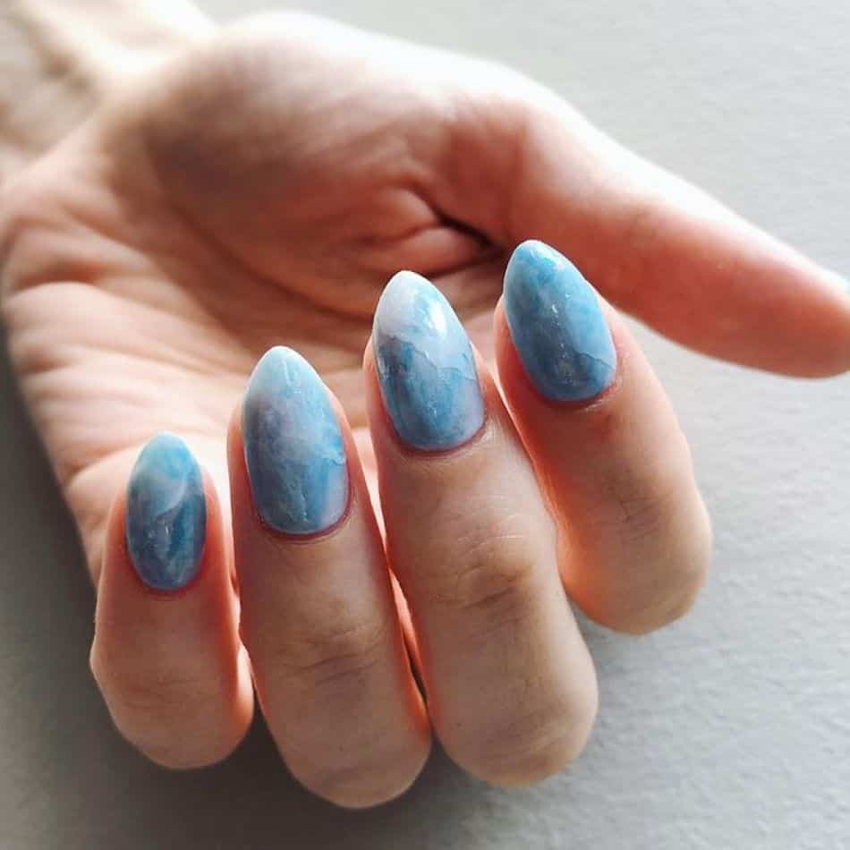 Marbled blue and white polish on short stiletto nails. 