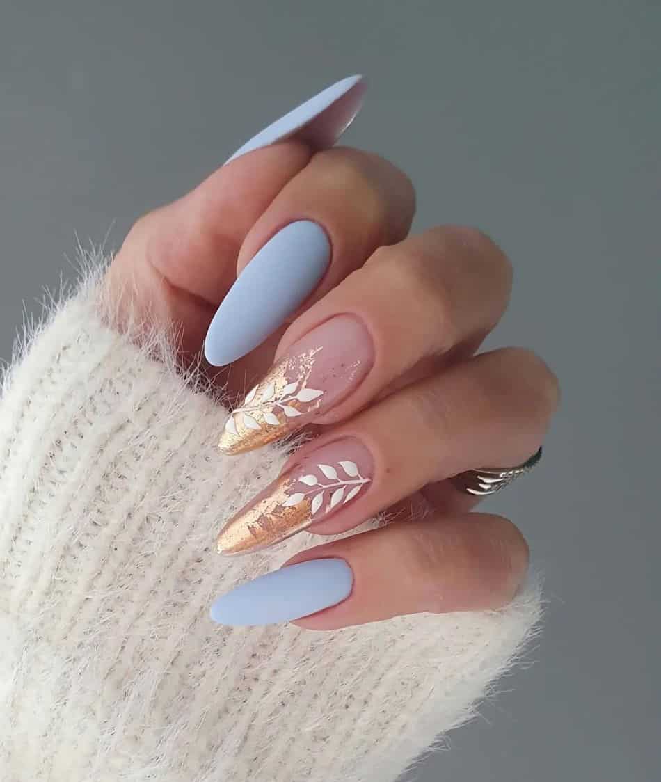 Pastel blue nails and gold tipped accent nails with white leaf art. 