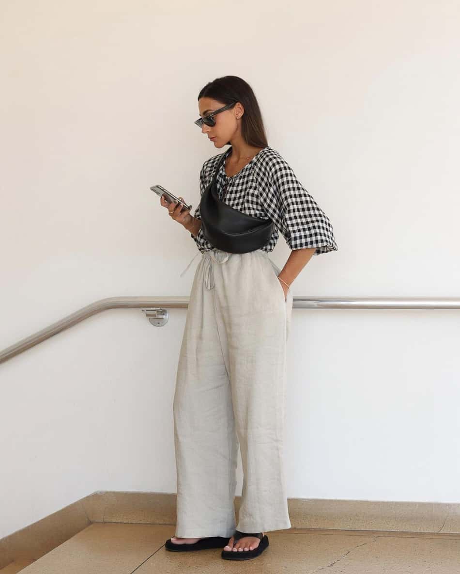 An image of a woman with white linen pants and a black and white checkered blouse