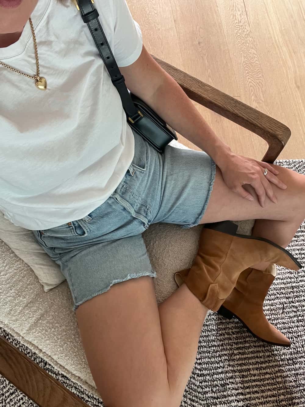 woman wearing a white t-shirt with jean shorts and brown western boots for a Nashville outfit