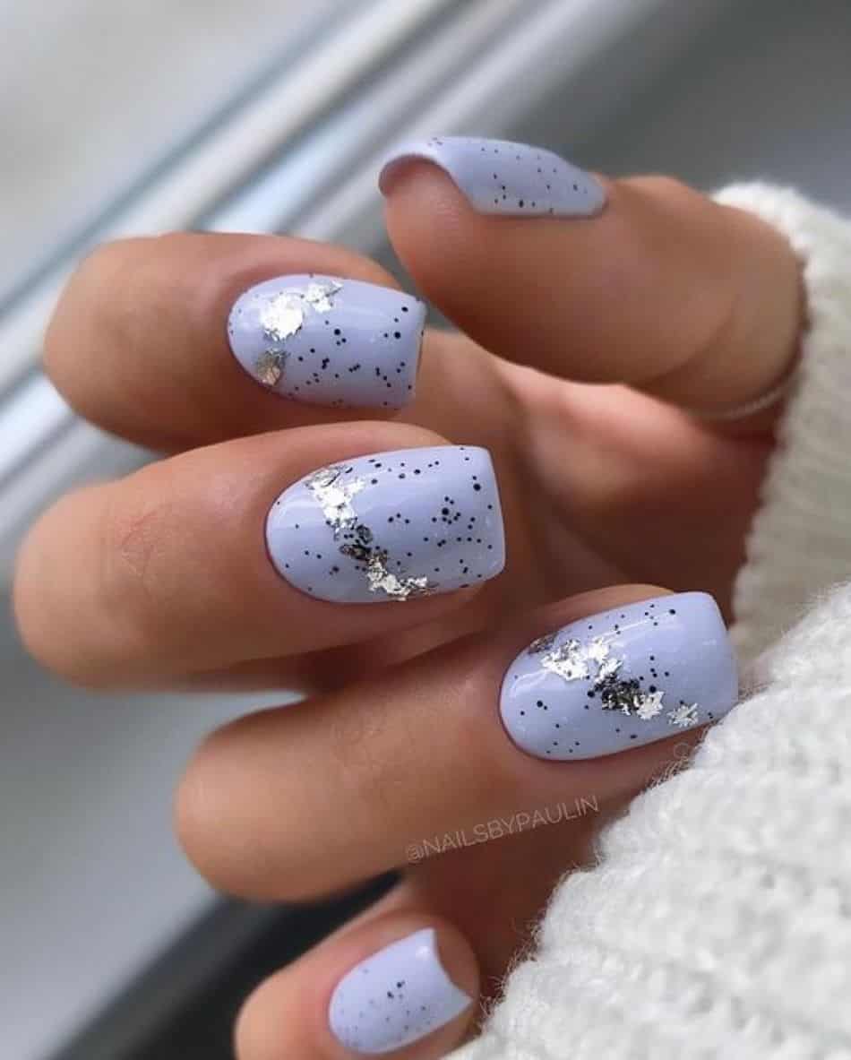A hand with light blue violet nails with silver glitter and flake accents