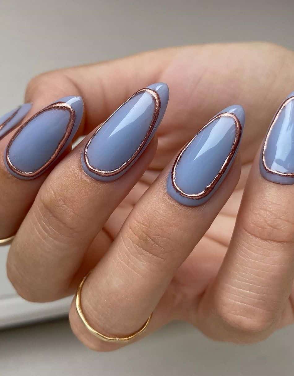 A hand with light blue violet nails and oval gold accents