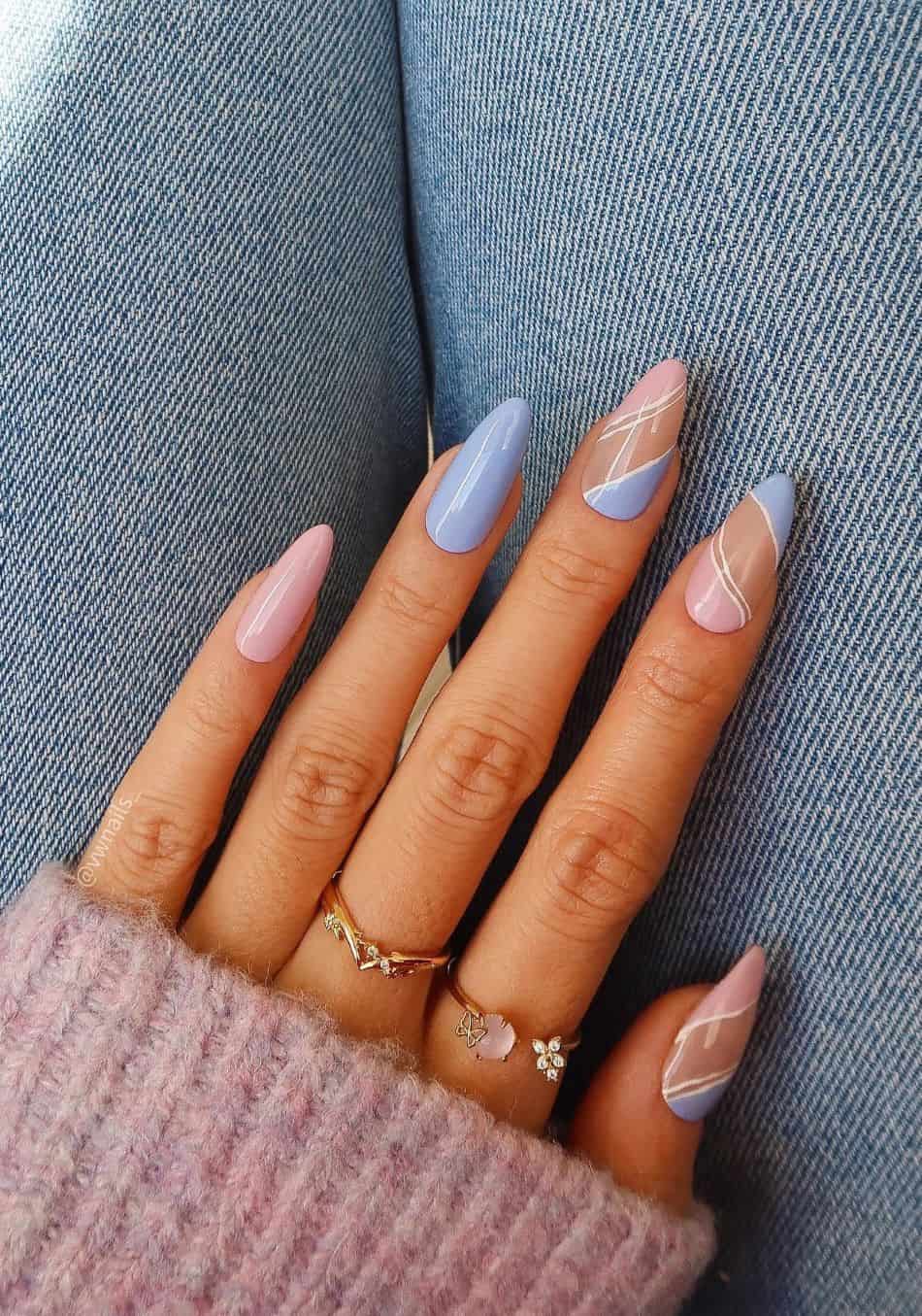 A hand with pink and periwinkle nails with white line details